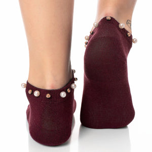 A woman wearing burgundy ankle socks embellished with pearls around the cuff