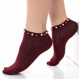 A woman wearing burgundy ankle socks embellished with pearls around the cuff