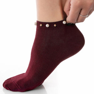 A woman wearing burgundy ankle socks embellished with pearls around the cuff