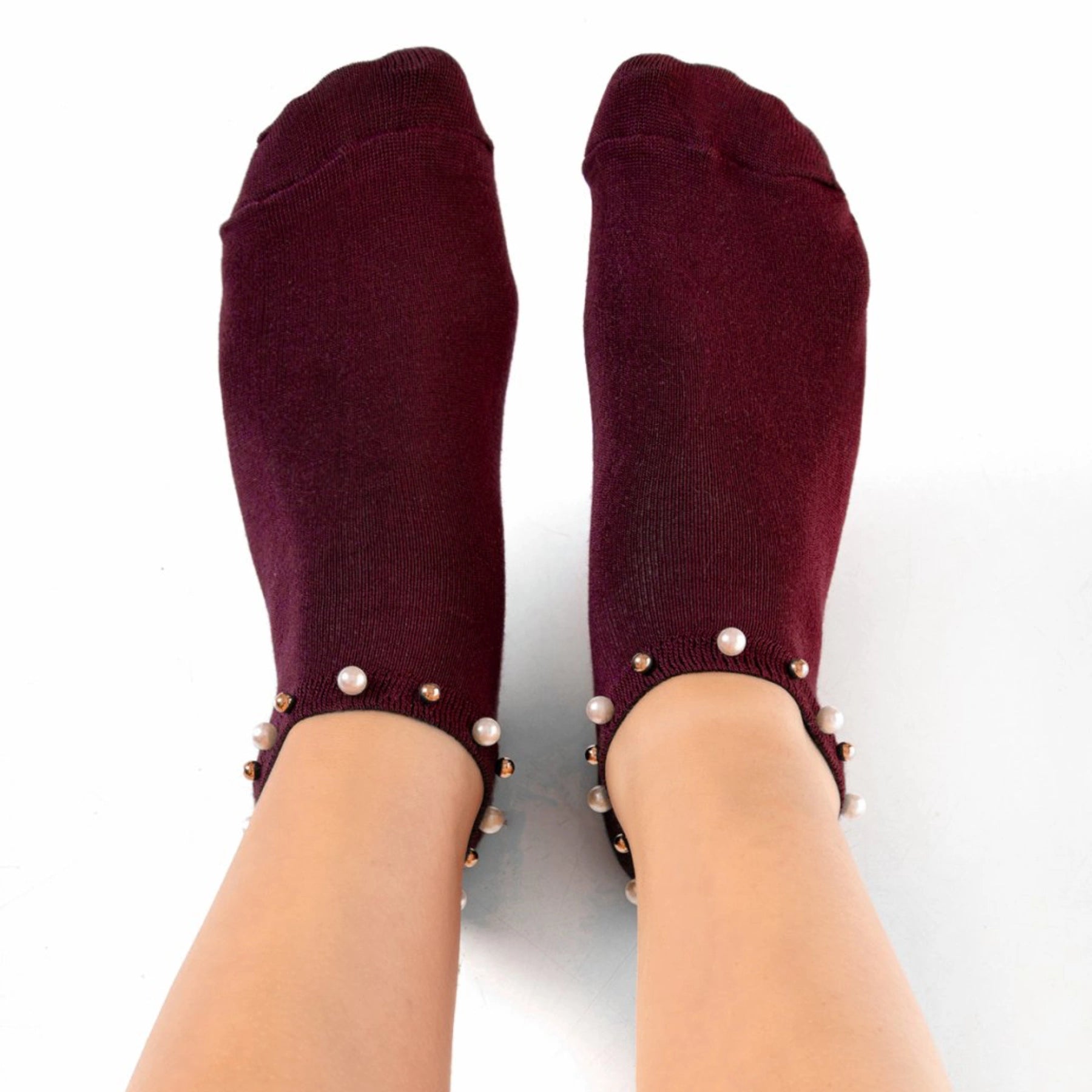 A woman wearing burgundy ankle socks embellished with pearls around the cuff