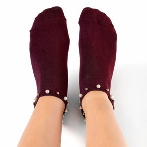 A woman wearing burgundy ankle socks embellished with pearls around the cuff