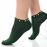 A woman wearing green ankle socks embellished with pearls around the cuff