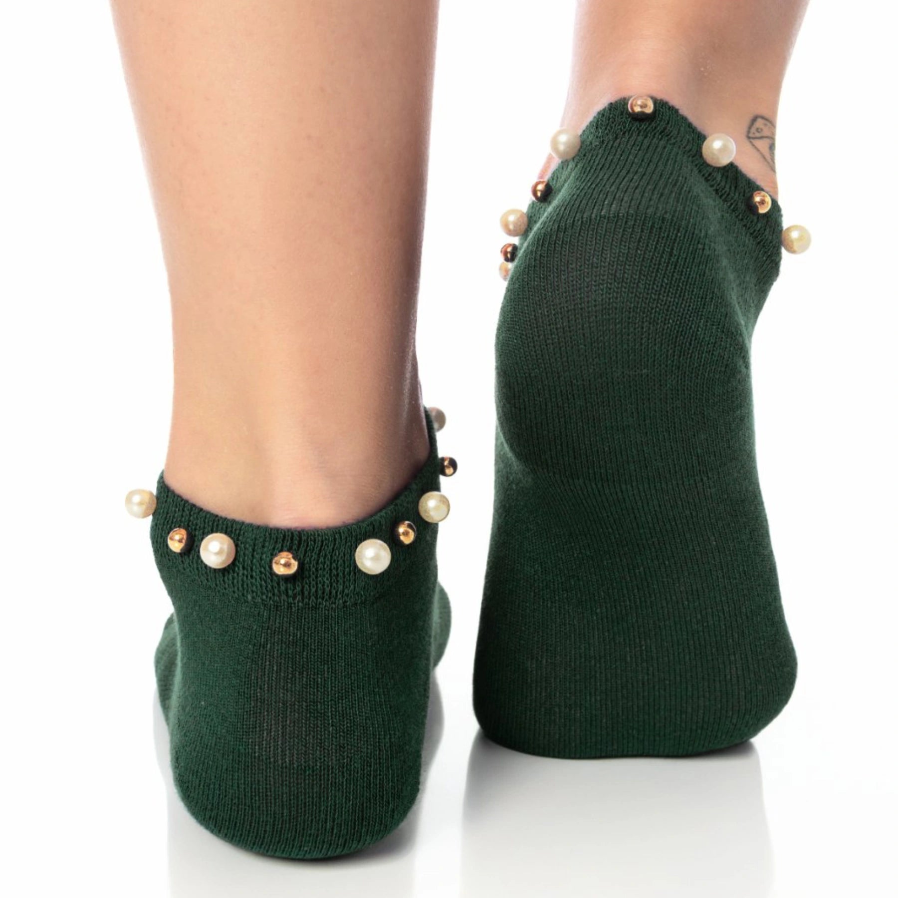 A woman wearing green ankle socks embellished with pearls around the cuff