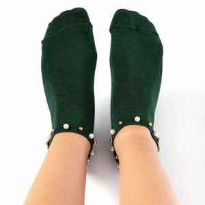 A woman wearing green ankle socks embellished with pearls around the cuff