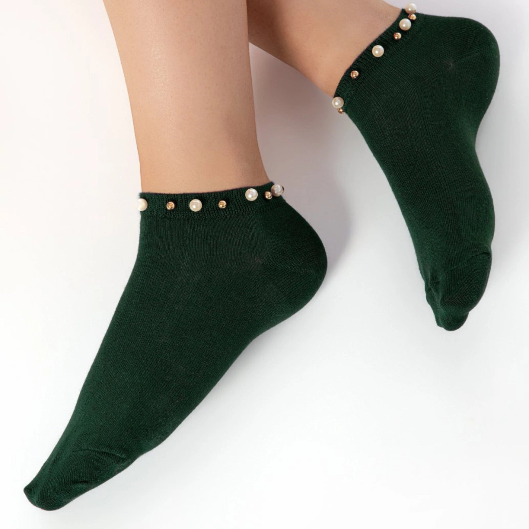 A woman wearing green ankle socks embellished with pearls around the cuff