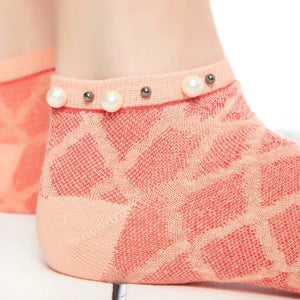 A closeup image of a woman wearing orange checked ankle socks embellished with pearls around the cuff