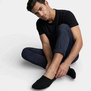 Man wearing black no-show socks sitting against a white background