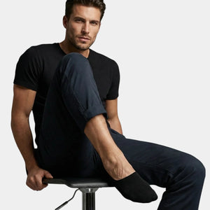 Man wearing black no-show socks sitting against a white background