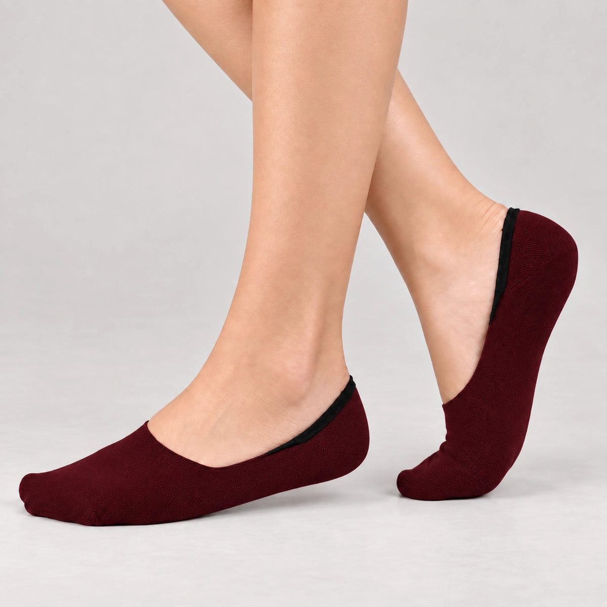 Person wearing burgundy bamboo no-show socks on a white background