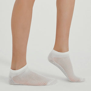 Photo of a person's legs wearing white, ventilated, non-slip, yoga and pilates socks