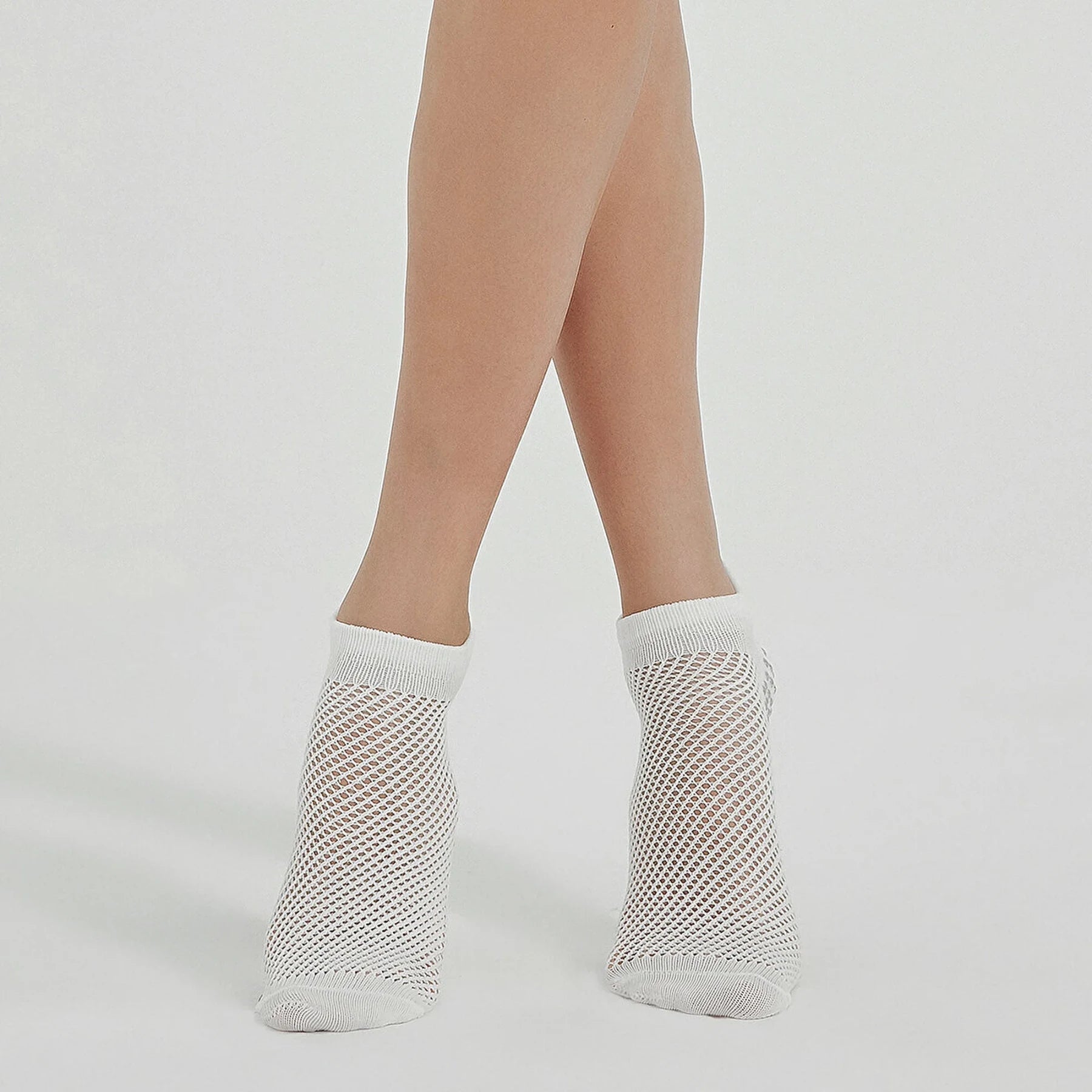 Photo of a person's legs wearing white, ventilated, non-slip, yoga and pilates socks