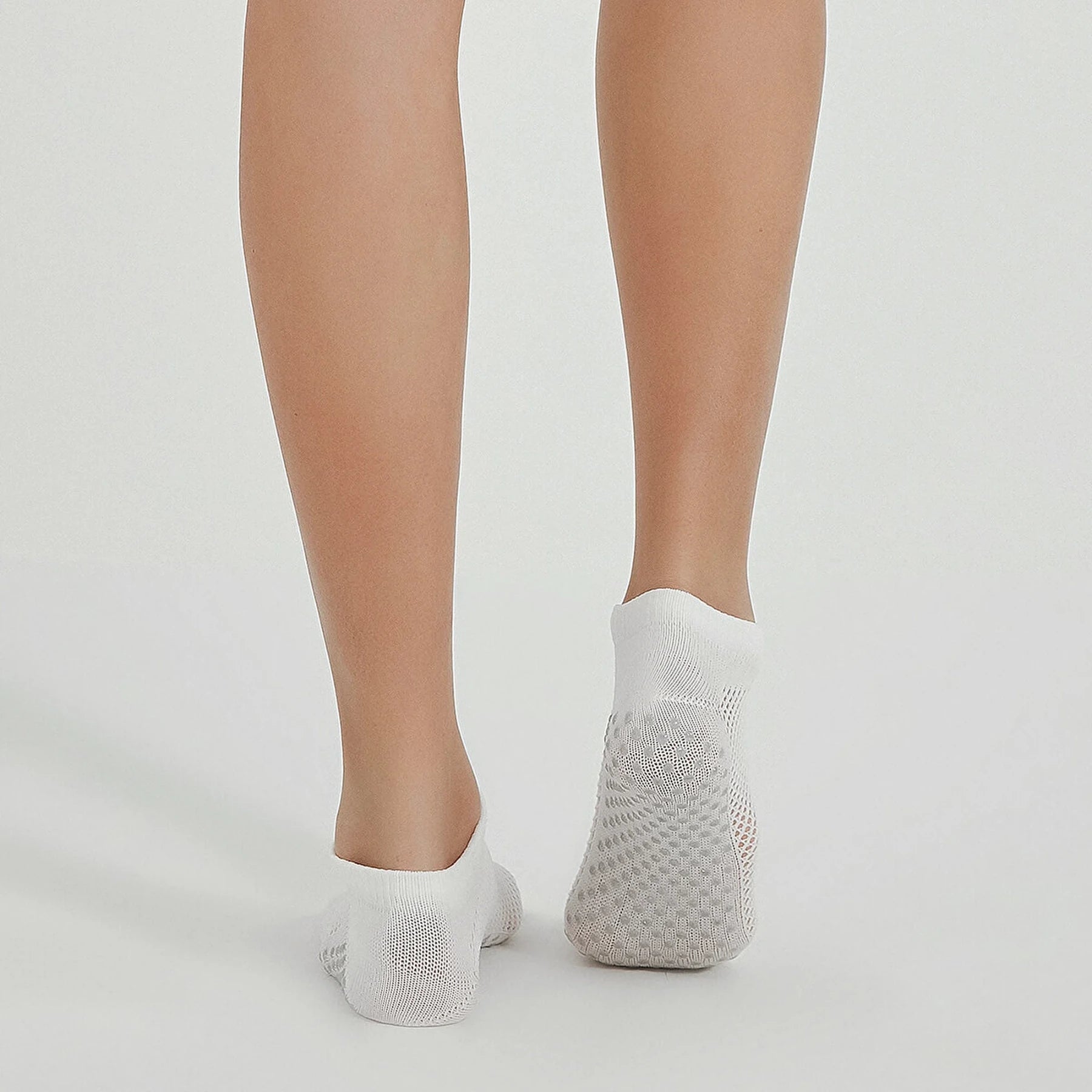 Photo of a person's legs wearing white, ventilated, non-slip, yoga and pilates socks