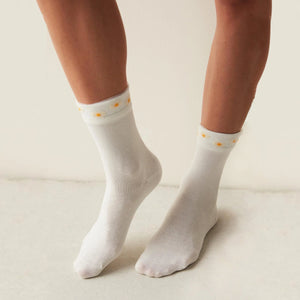 Person wearing ivory coloured quarter length socks with delicate yellow daisies on a sheer cuff