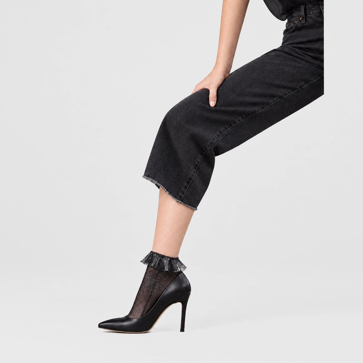 person wearing black and silver quarter length socks with frilled cuff and high heel shoes
