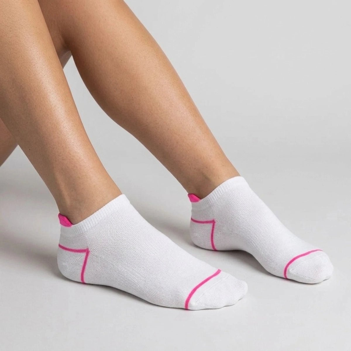 White ankle socks with pink accents worn by a person on a light grey background