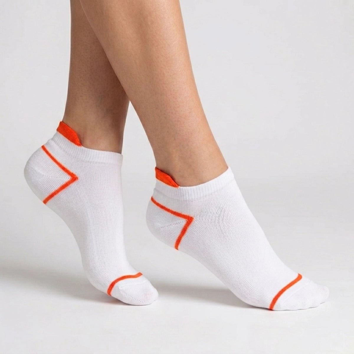 White ankle socks with orange accents worn by a person on a light grey background