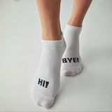 Person wearing white socks with the right foot stating Hi! and the left foot stating Bye!