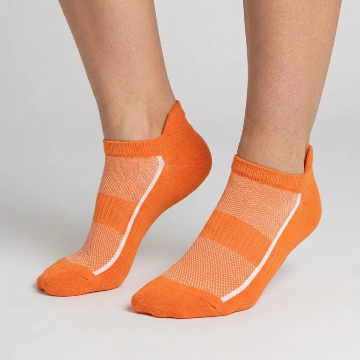 Orange ankle socks with mesh design worn by a person on a light gray background