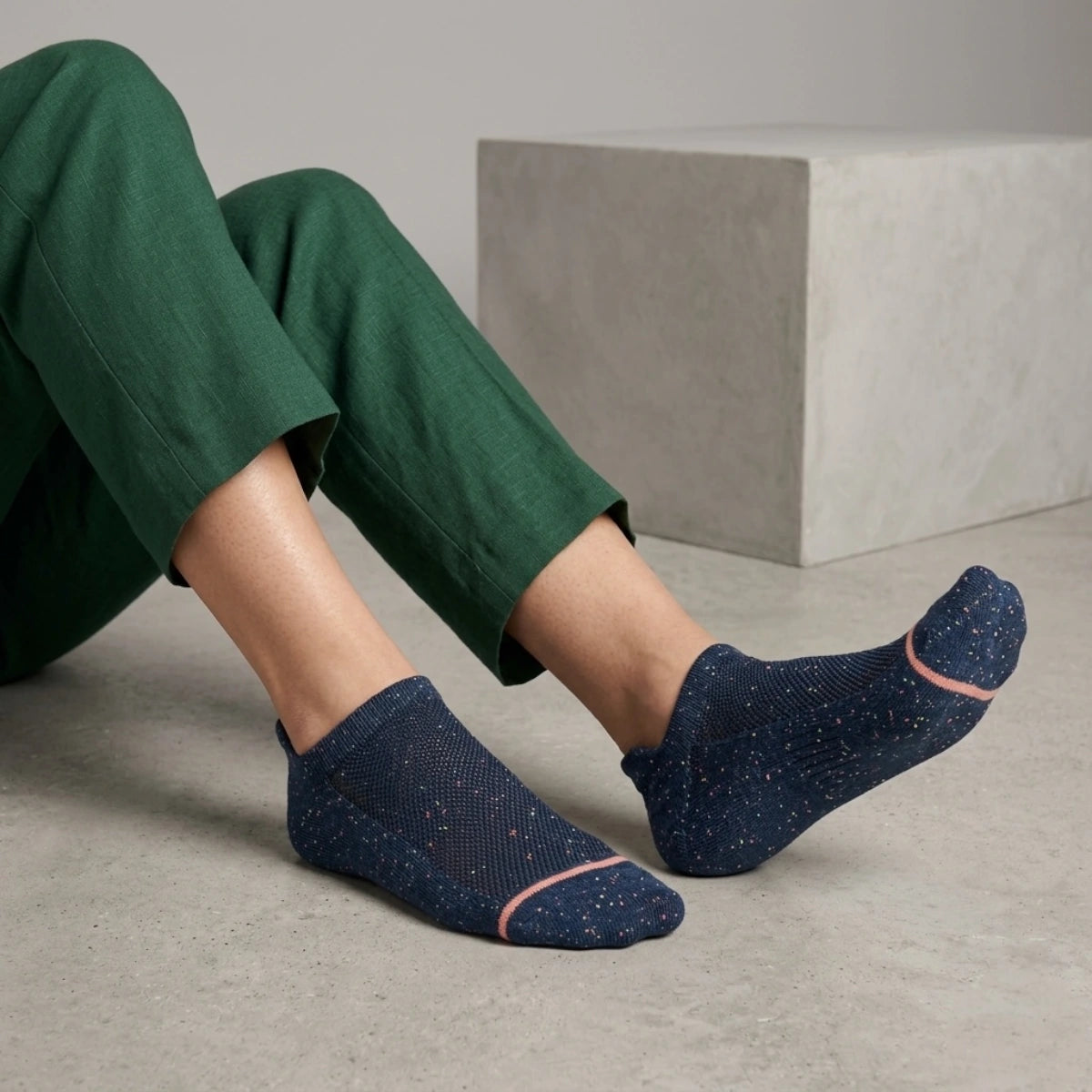 Blue socks with speckled accents worn by a person in green pants on a neutral background