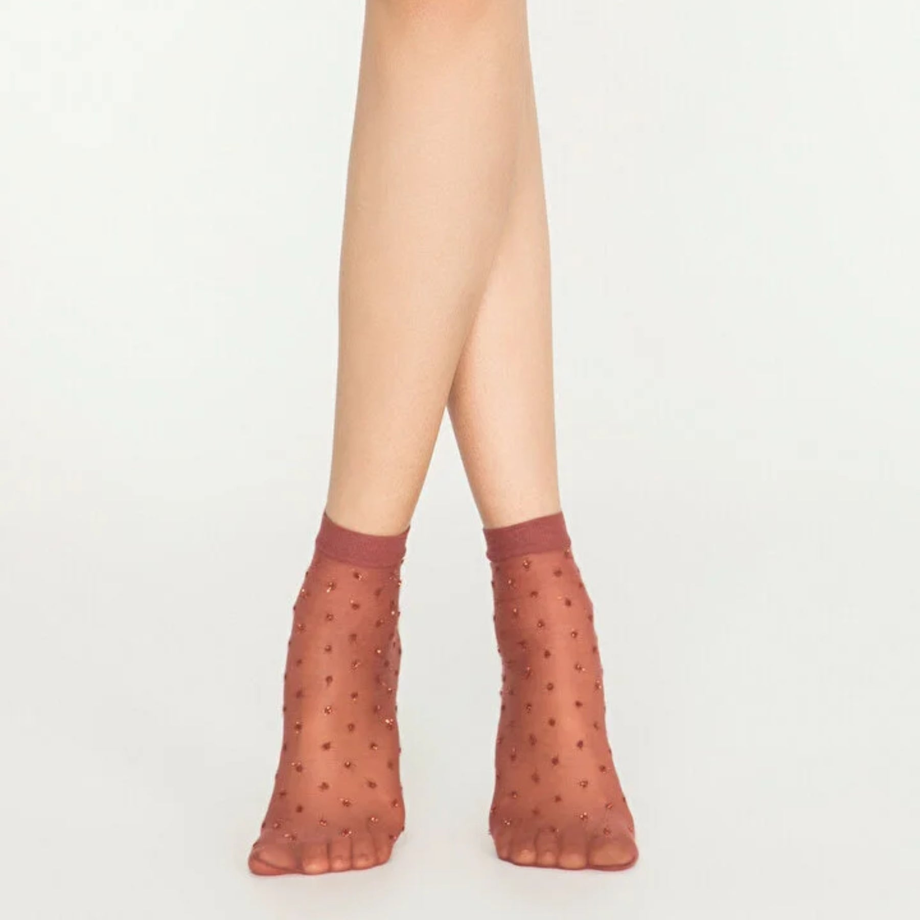Woman wearing sheer cinnamon ankle socks with sparkling gold dots on white background