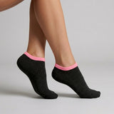 Person wearing black seamless ankle socks with pink cuff against a neutral background
