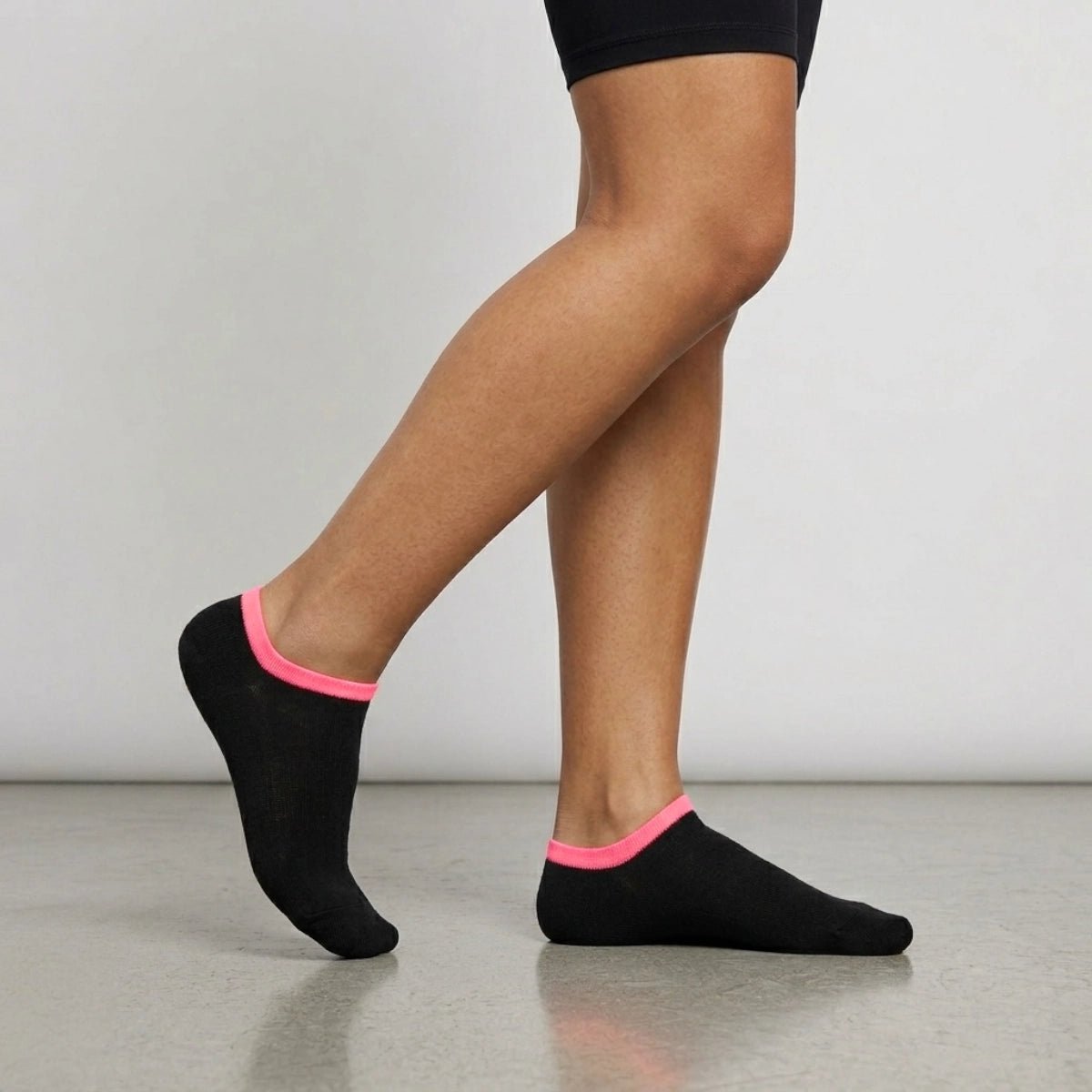 Person wearing black seamless ankle socks with pink cuff against a neutral background