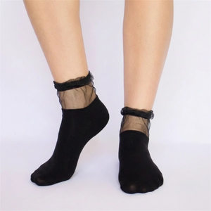 Black socks with sheer mesh cuff worn by a person on a white background