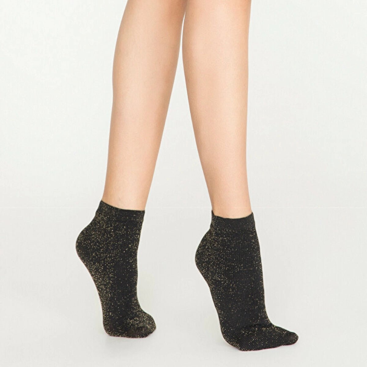 Woman wearing black and gold, sparkly ankle sock