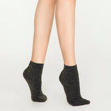 Woman wearing black and gold, sparkly ankle sock