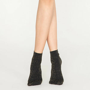 Woman wearing black and gold, sparkly ankle sock