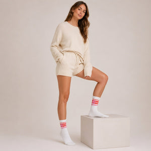 A person in a cream outfit wearing white tennis socks with pink Prince branding against a light background
