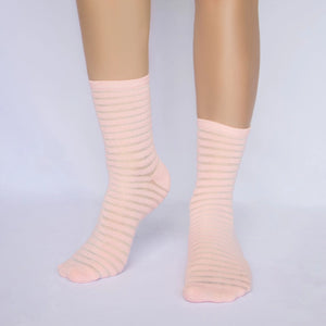 A person wearing salmon socks with thin sheer stripes on a grey background