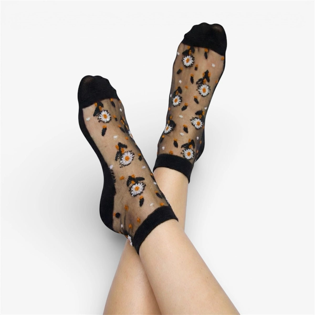Sheer socks with white daisy pattern worn by a person on a white background