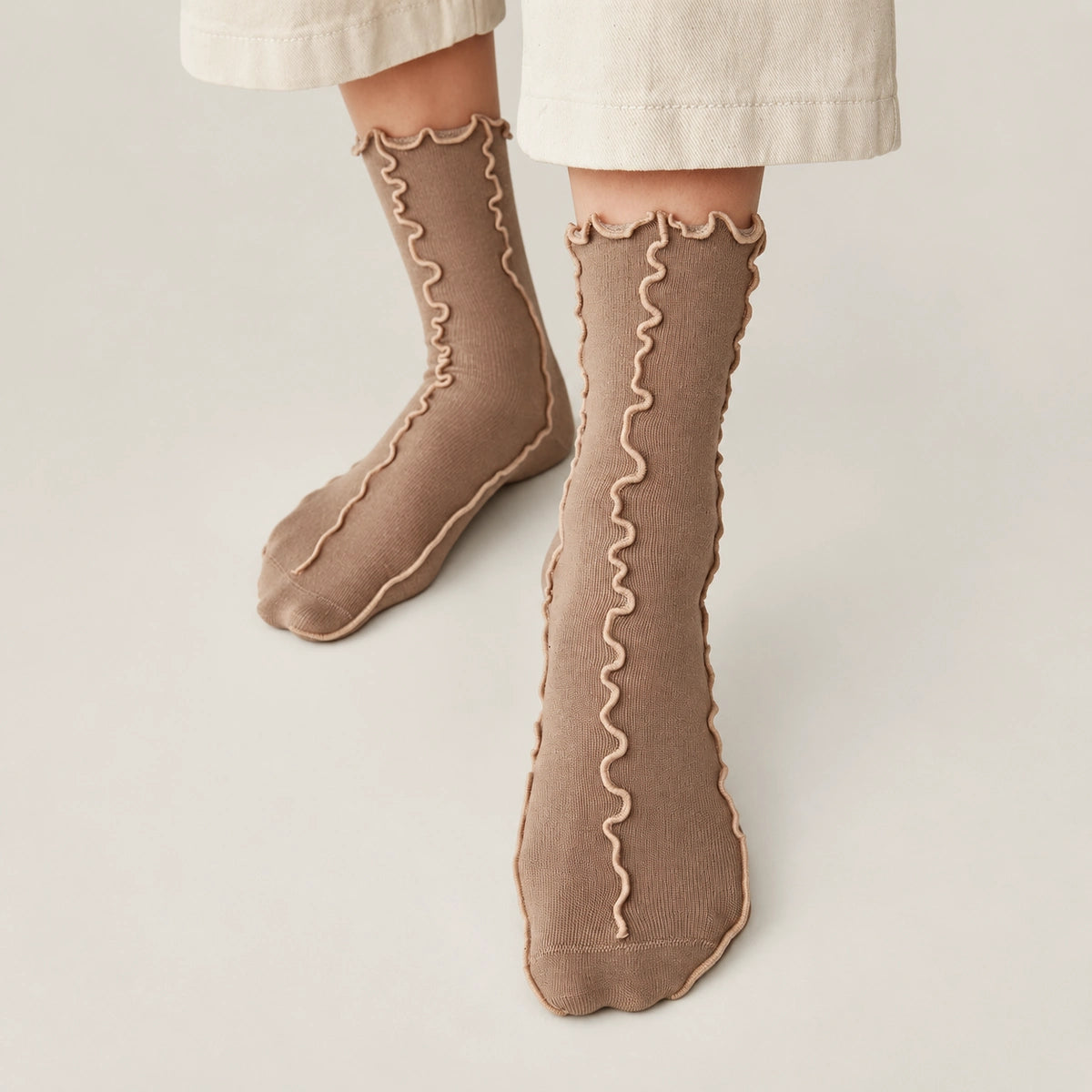 Person wearing coffee coloured, frilled socks