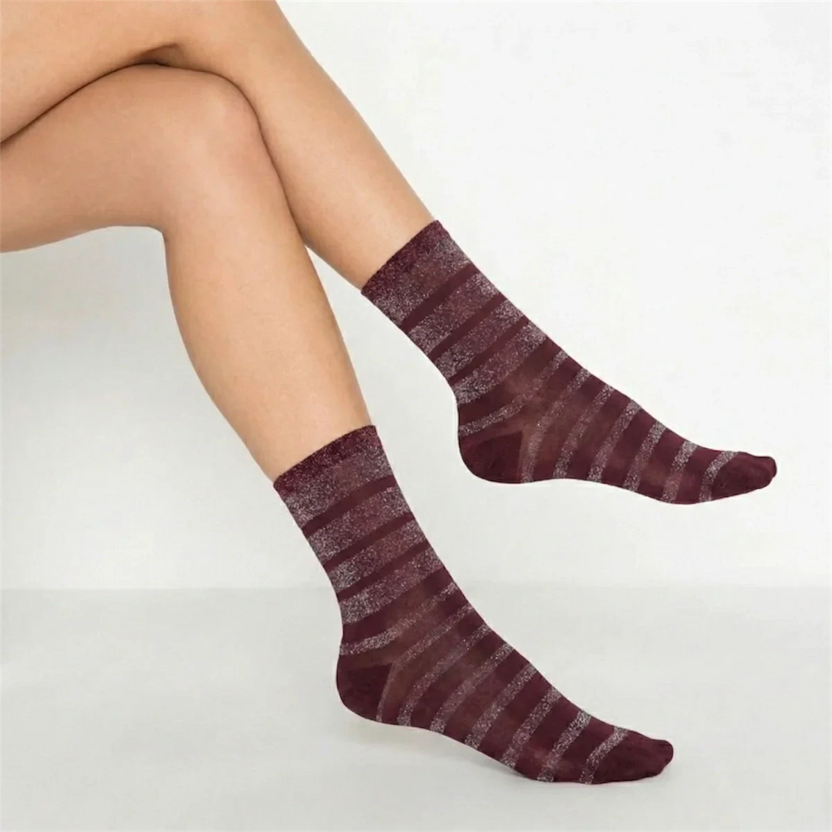 person wearing burgundy and gold striped crew socks on a light background