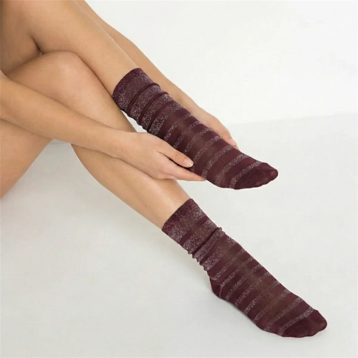person wearing burgundy and gold striped crew socks on a light background