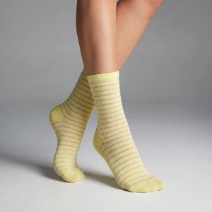 A Person wearing yellow socks with thin sheer stripes on a grey background