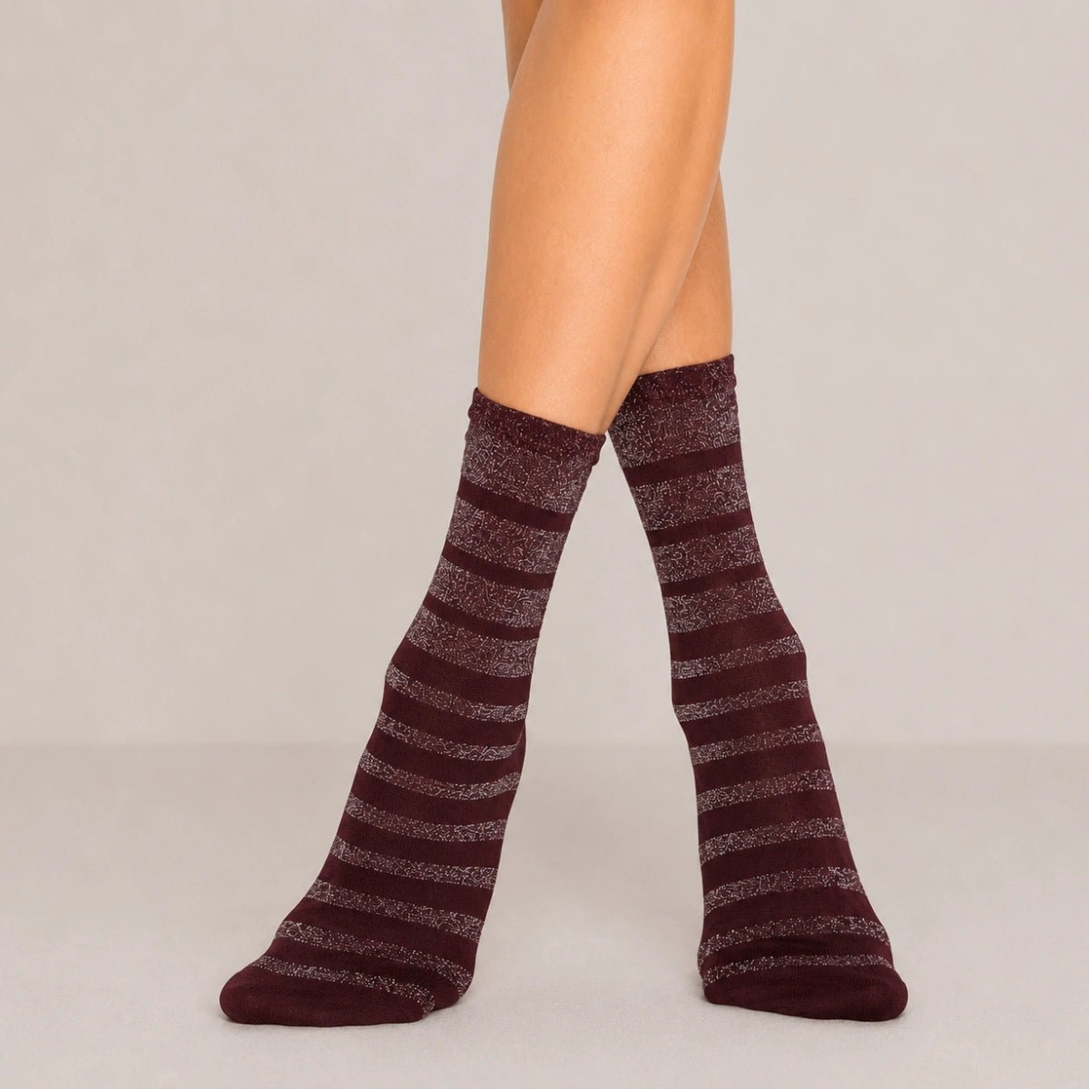 Burgundy glitter stripe women’s crew socks with metallic shimmer detail, styled standing against a soft neutral background