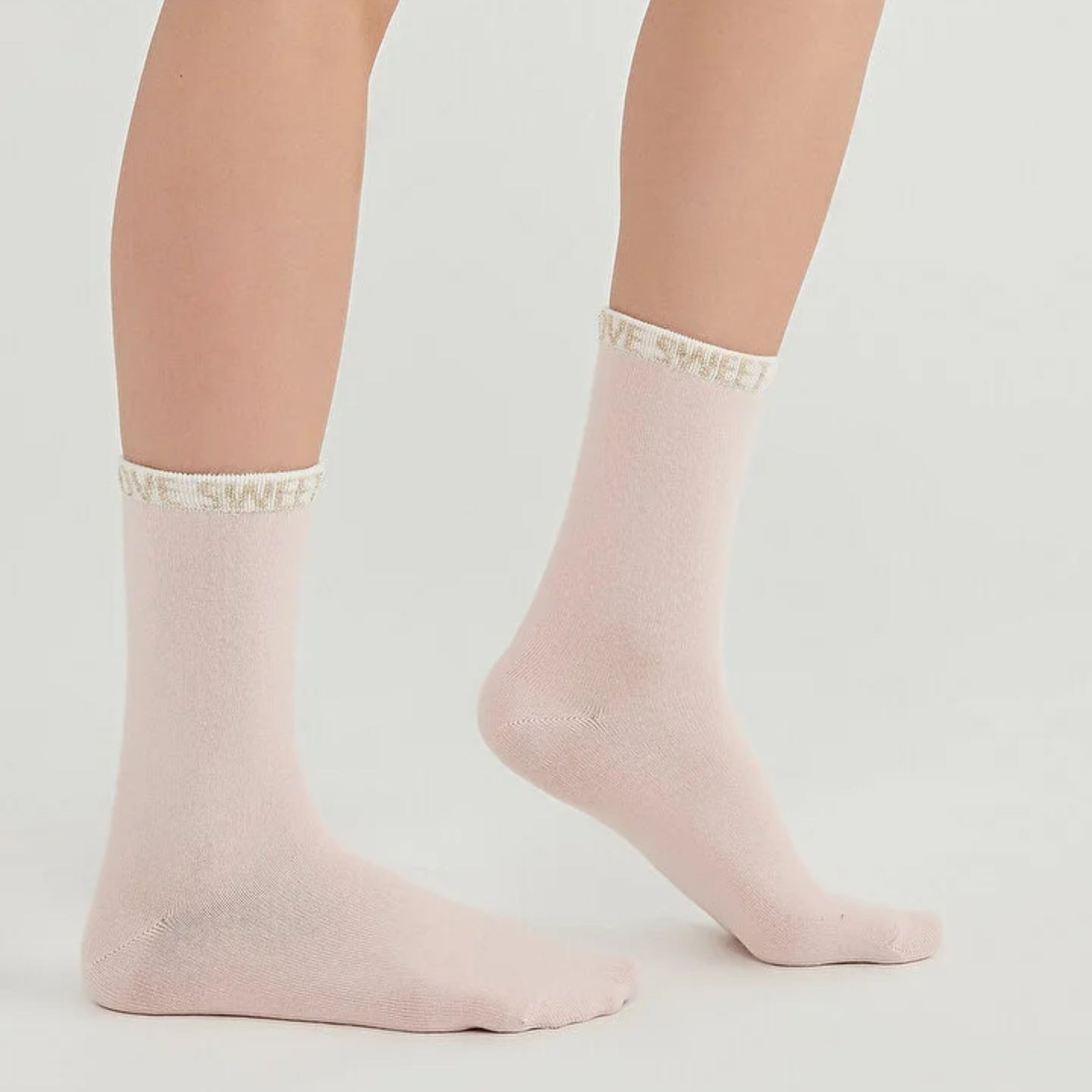 Woman wearing pale pink crew socks with 'Love Sweet' slogan around the cuff