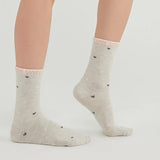 Woman wearing pale grey crew socks with 'Love Sweet' slogan around the cuff and love hearts scattered over the sock