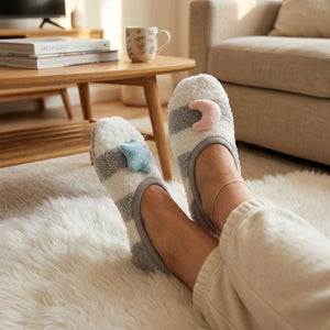 Person wearing mismatched grey and white striped loungewear socks with a cute star and moon applied