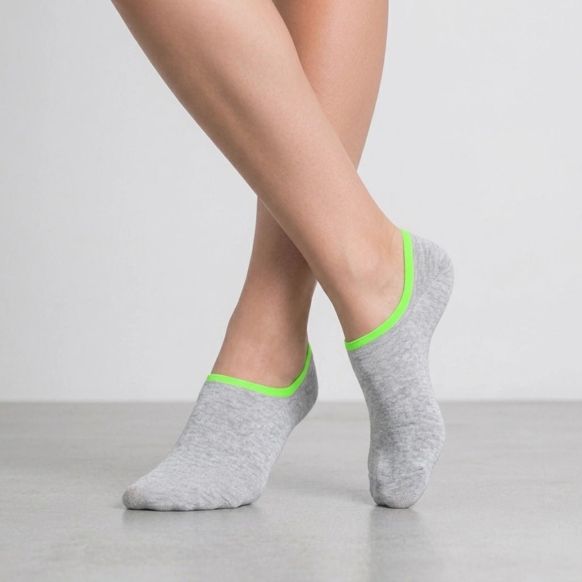Person wearing grey no-seam ankle socks with green cuff against a light background
