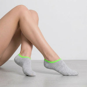 Person wearing grey no-seam ankle socks with green cuff against a light background