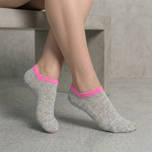 Person wearing grey no-seam ankle socks with pink cuff against a light background