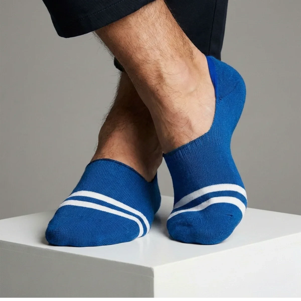 Blue no-show socks with white stripes worn by a person on a neutral background