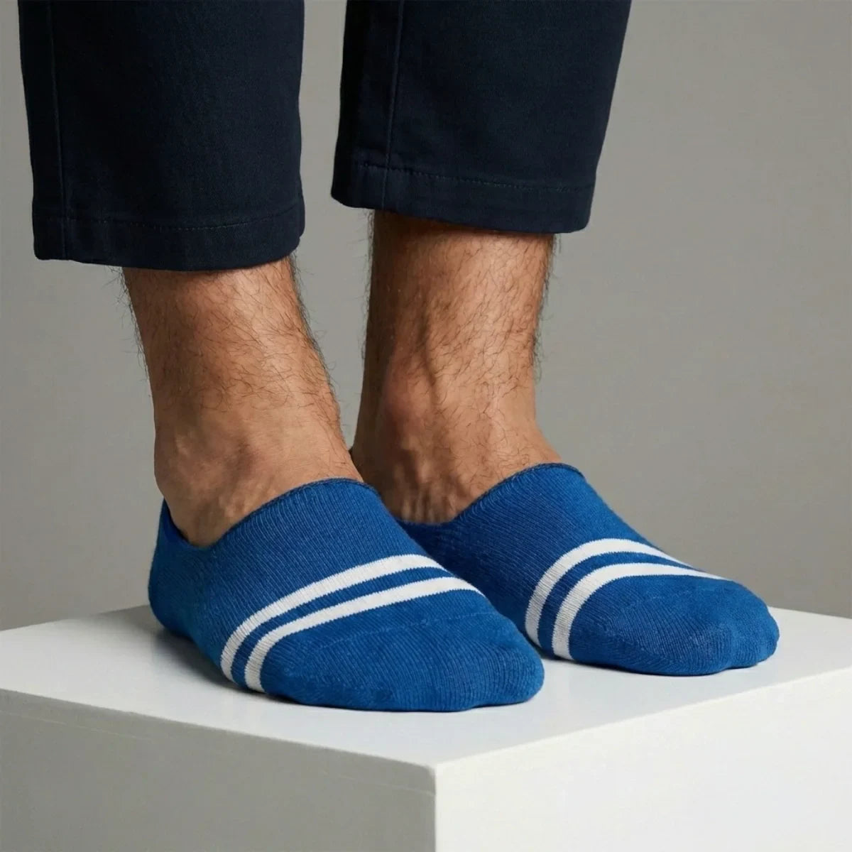 Blue no-show socks with white stripes worn by a person on a neutral background