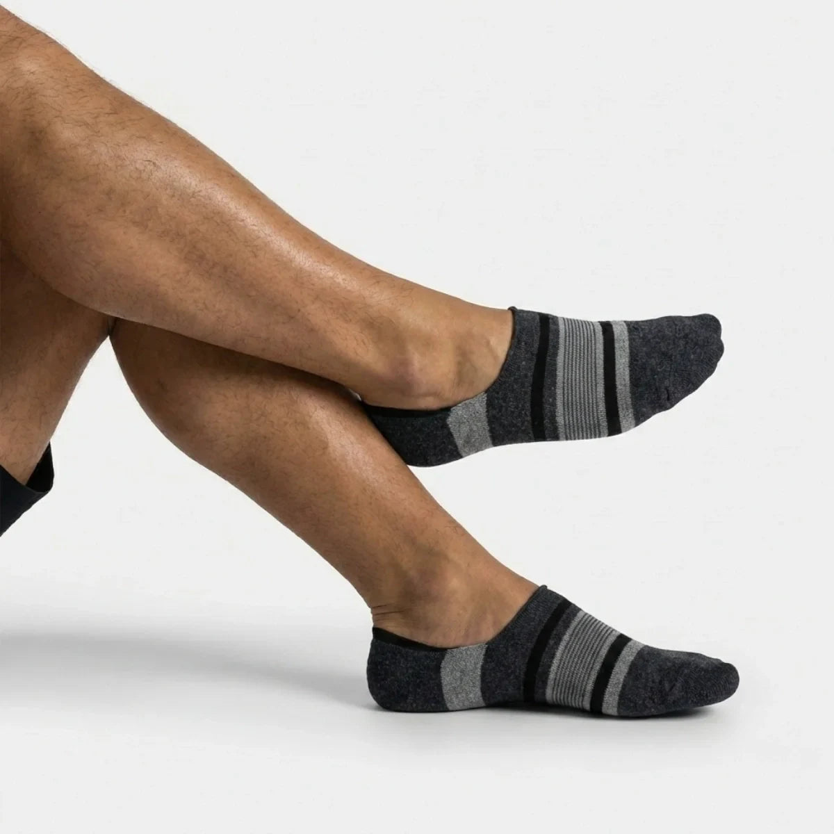 Grey striped no-show socks worn by a person on a white background