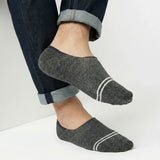 Person wearing dark grey no-show socks with white stripes on a light background