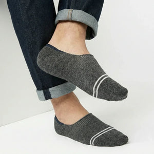 Person wearing dark grey no-show socks with white stripes on a light background