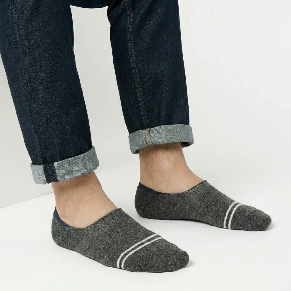 Person wearing dark grey no-show socks with white stripes on a light background